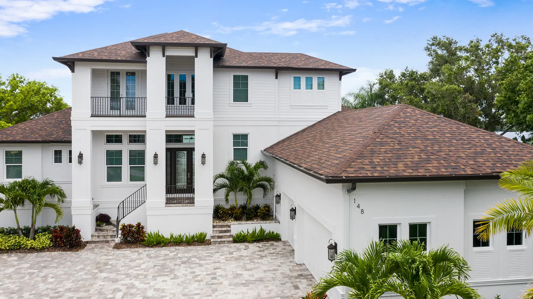 Waterfront luxury home with a modern design, spacious patio, swimming pool, and landscaped outdoor seating area, built by Gulf Wind Homes.