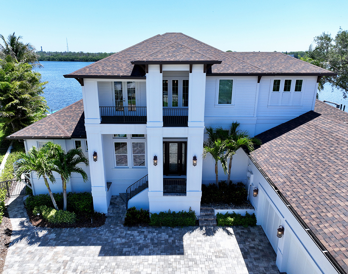Waterfront luxury home with a modern design, spacious patio, swimming pool, and landscaped outdoor seating area, built by Gulf Wind Homes.