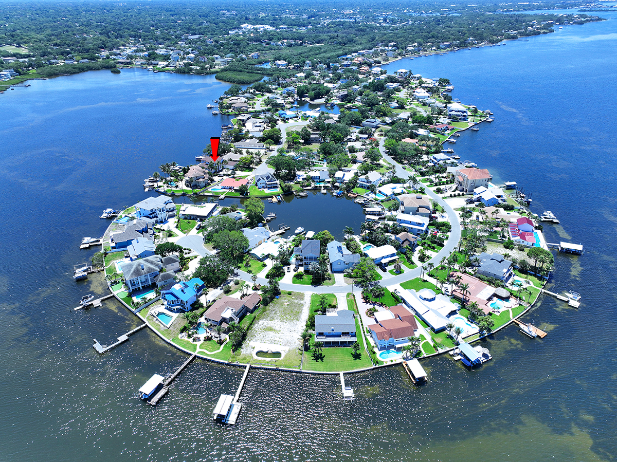 Waterfront luxury home with a modern design, spacious patio, swimming pool, and landscaped outdoor seating area, built by Gulf Wind Homes.